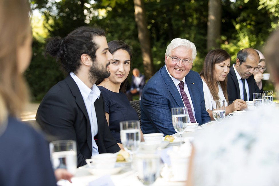 Bundespräsident Frank-Walter Steinmeier tauscht sich während eines Gesprächs mit Bürgerinnen und Bürgern aus der Nachbarschaft bei einer türkisch-deutschen Kaffeetafel im Schlosspark aus